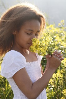 Mixed race girl smelling flowers