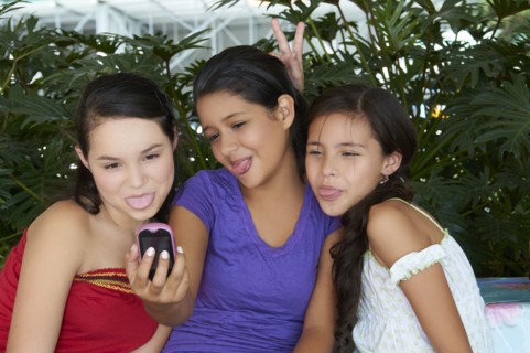 Hispanic girls taking self-portrait with cell phone