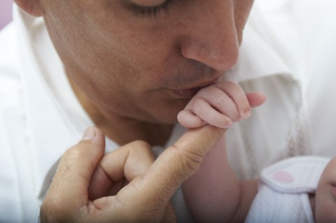 Hispanic father kissing baby daughter's hand