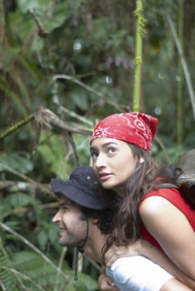 Hispanic man giving girlfriend piggyback ride in forest