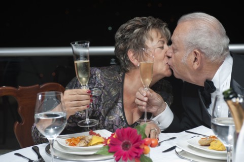 Kissing Hispanic couple toasting with Champagne in restaurant