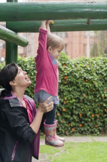Hispanic mother helping daughter in playground