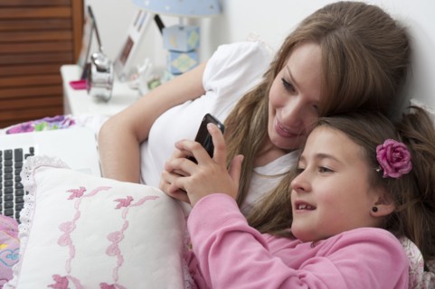 Hispanic mother and daughter looking at cell phone