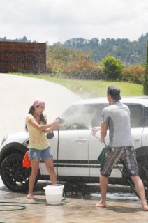 Playful Hispanic couple washing car together