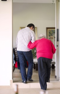 Hispanic man helping his grandmother to walk