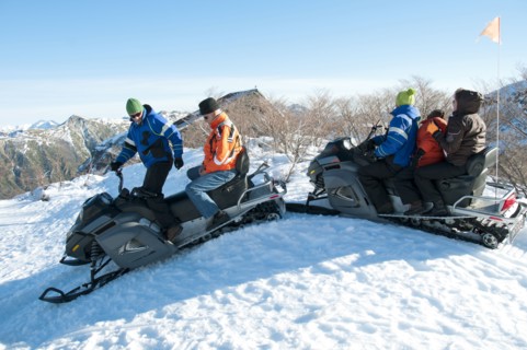 Hispanic family riding on snowmobiles through snow