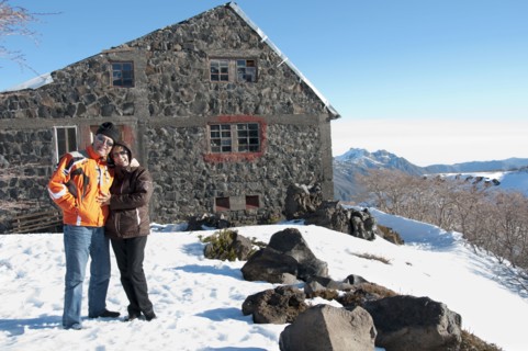 Hispanic couple standing in snow near house
