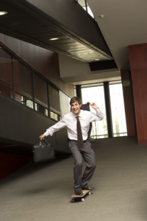 Hispanic businessman riding on skateboard