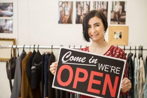 Hispanic woman holding open sign