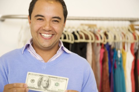 Hispanic man holding cash in clothing store