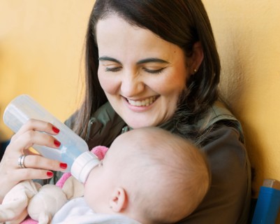 Hispanic mother feeding baby daughter