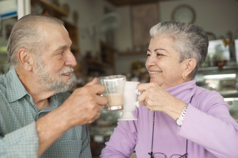 Hispanic couple toasting with coffee cups in cafe