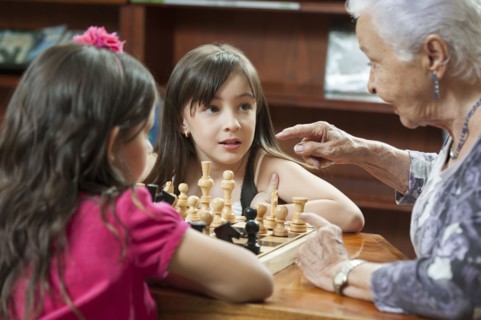 Hispanic grandmother and granddaughters playing chess