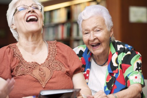 Senior Hispanic woman laughing and using digital tablet