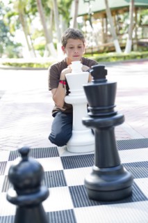 Hispanic boy playing with oversized chess set