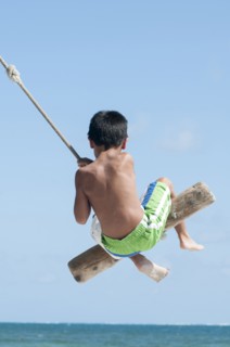 Hispanic boy playing on swing outdoors