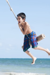 Hispanic boy playing on swing outdoors