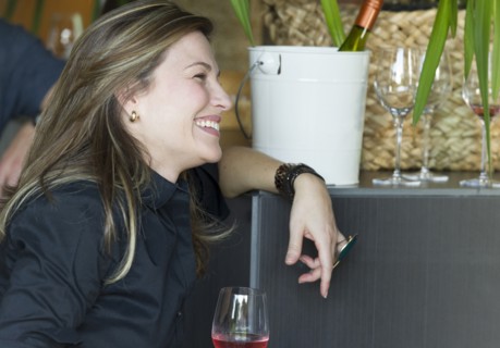 Hispanic woman drinking glass of wine at party