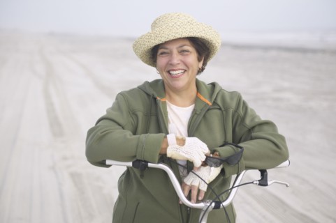 Senior woman with bicycle on beach