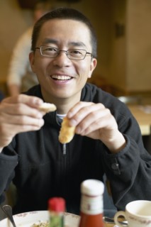 Asian man eating in restaurant