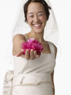 Asian woman in wedding dress holding flower