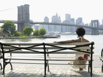 African woman sitting on bench at urban waterfront