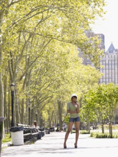 Hispanic woman text messaging on cell phone in park