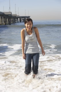 Asian woman wading near pier at beach