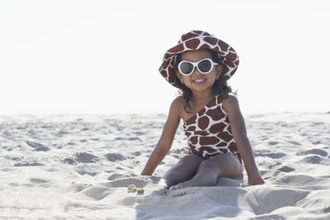 Young mixed race girl in sunglasses sitting at beach