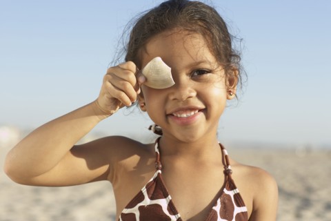 Young mixed race girl holding shell at beach