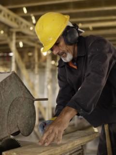 Hispanic worker using saw at construction site
