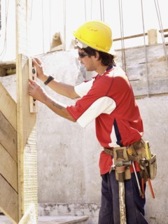 Hispanic worker using level on construction site