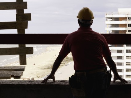Hispanic worker looking down from construction site