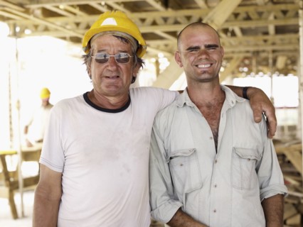 Hispanic workers hugging construction site