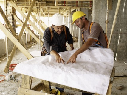 Hispanic workers looking at blueprints on construction site