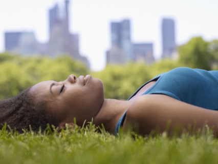 African woman laying on grass in park