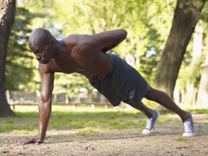 African man doing one arm push-ups in park