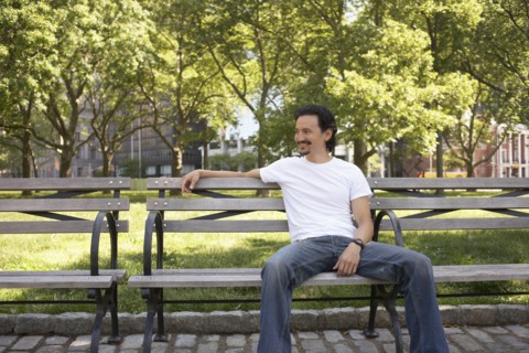 Mixed race man relaxing on park bench