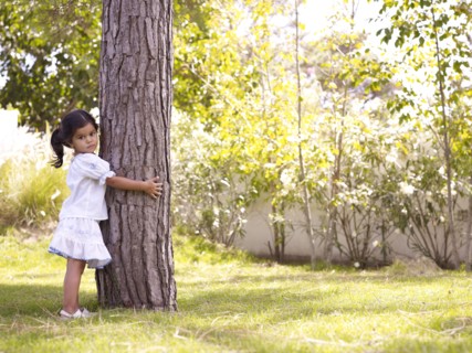 Hispanic girl hugging tree trunk
