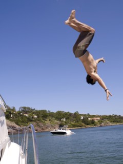 Hispanic man jumping from sailboat