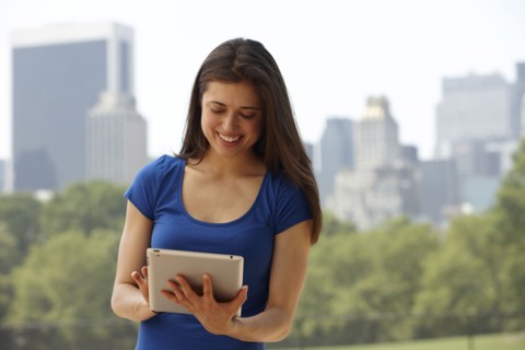 Caucasian woman using digital tablet in city park