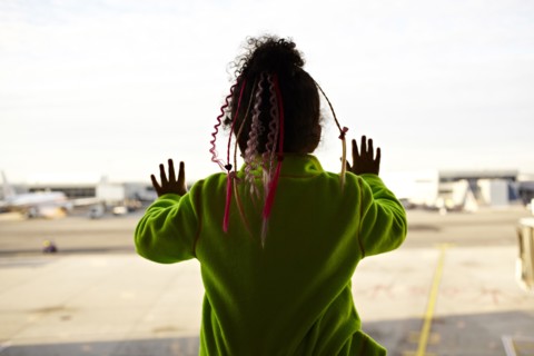Mixed race girl looking out airport window