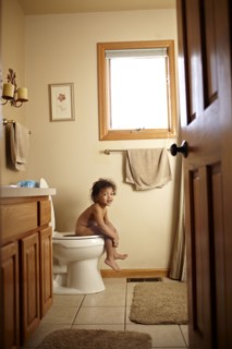 Nude mixed race toddler using toilet