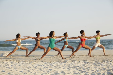 Women practicing yoga on beach