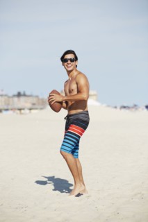 Man playing with football on beach