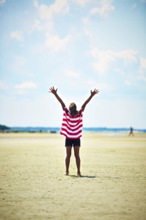 Black girl standing with arms raised on beach