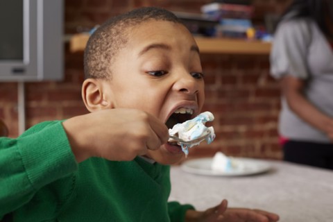 Black boy eating cake at table