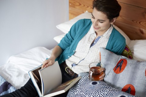 Woman drinking tea and reading in bed