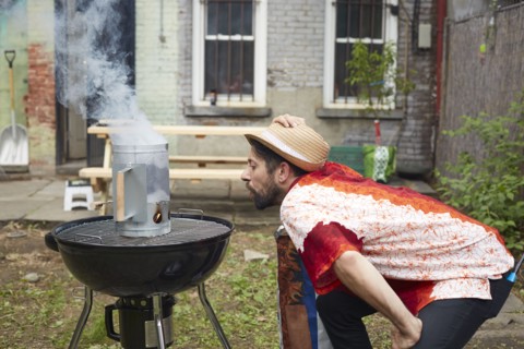 Caucasian man lighting charcoal for grill in backyard