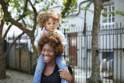 Mother carrying daughter on shoulders outdoors